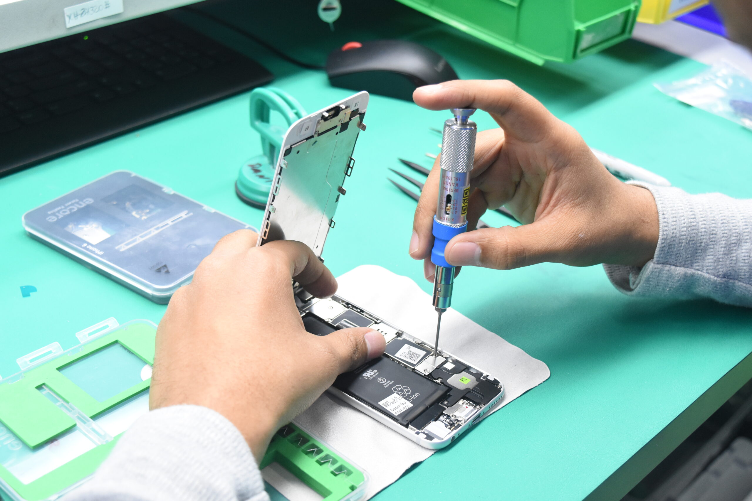 A person working on repairing a smartphone on top of a workbench